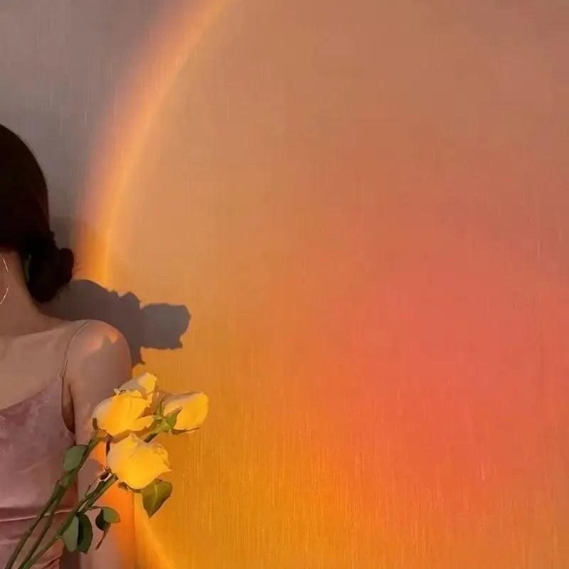 USB Sunset Projection Lamp creating a warm sunset glow on a wall, featuring a woman holding yellow roses.