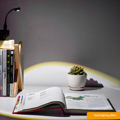 USB Sunset Projection Lamp creating a warm ambiance on an open book with a plant in the background.